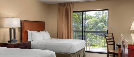 A hotel room with two beds, a desk, a chair, and a balcony with a view.