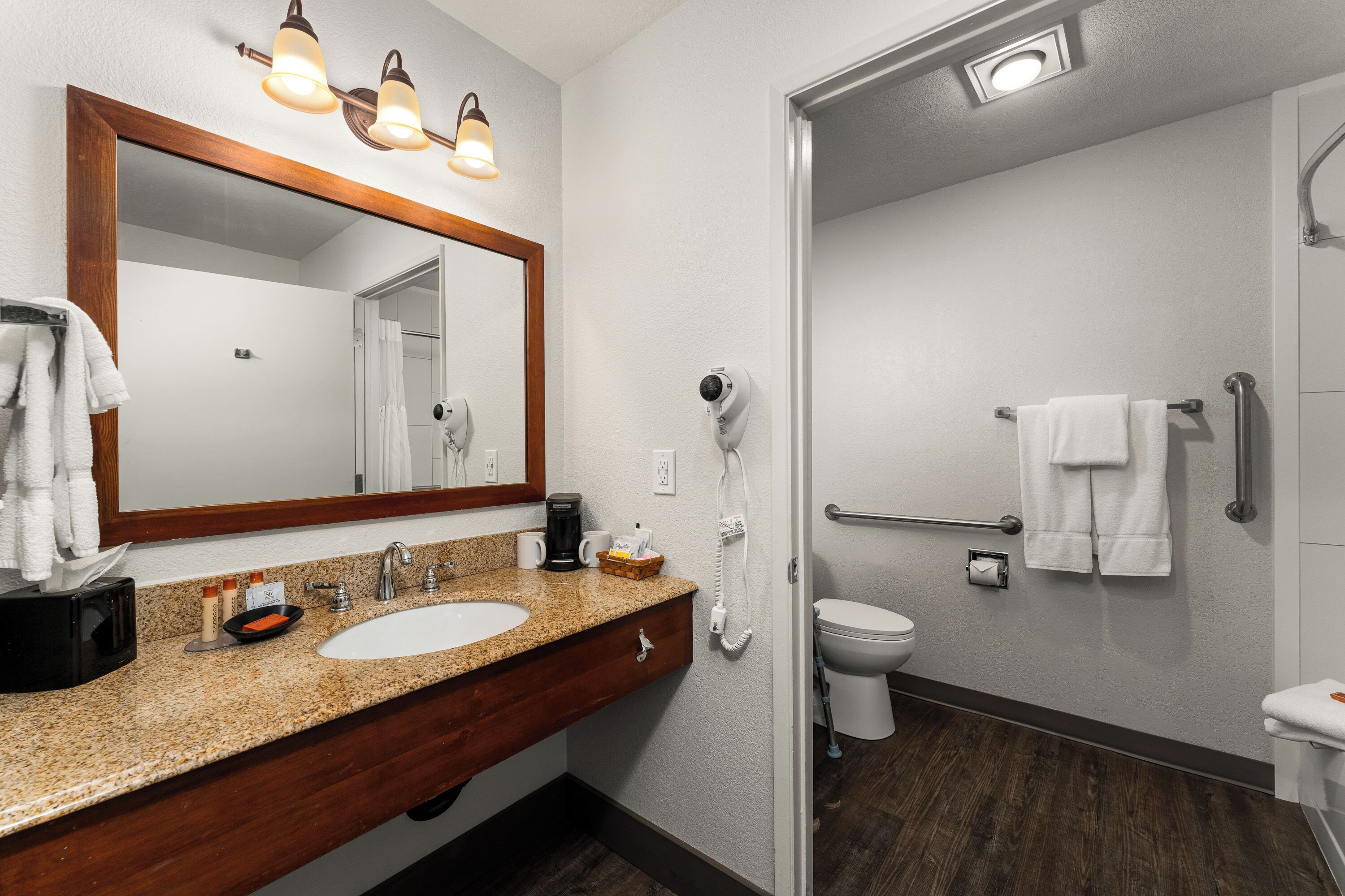 Een badkamer met een wastafel, spiegel, handdoekrek, toilet en een haardroger.