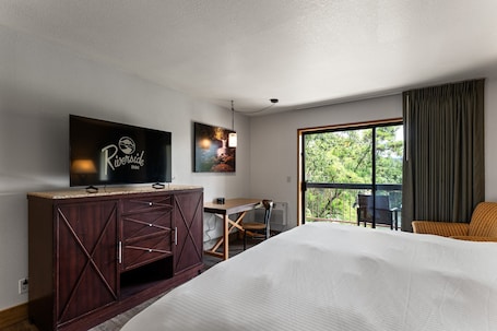 A hotel room with a bed, a desk, a television, and a large window.