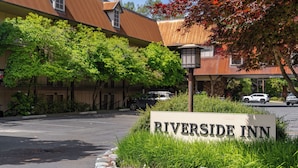 Señal de Riverside Inn, con un estacionamiento y árboles al fondo.