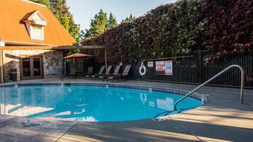 En säsongsöppen utomhuspool, parasoller och solstolar