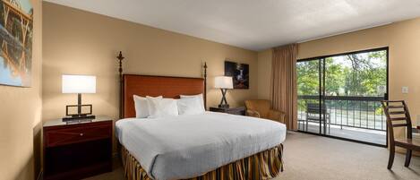 A hotel room with a large bed, a nightstand, a desk, a chair, a window with a view, and a painting on the wall.