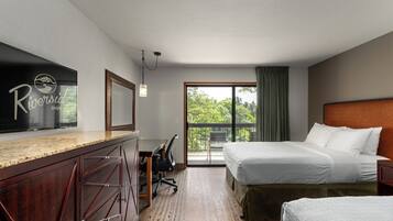 A hotel room with a bed, a desk, a chair, and a large window.