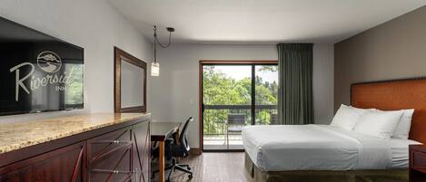 Een hotelkamer met een bed, een bureau, een stoel en een groot raam.