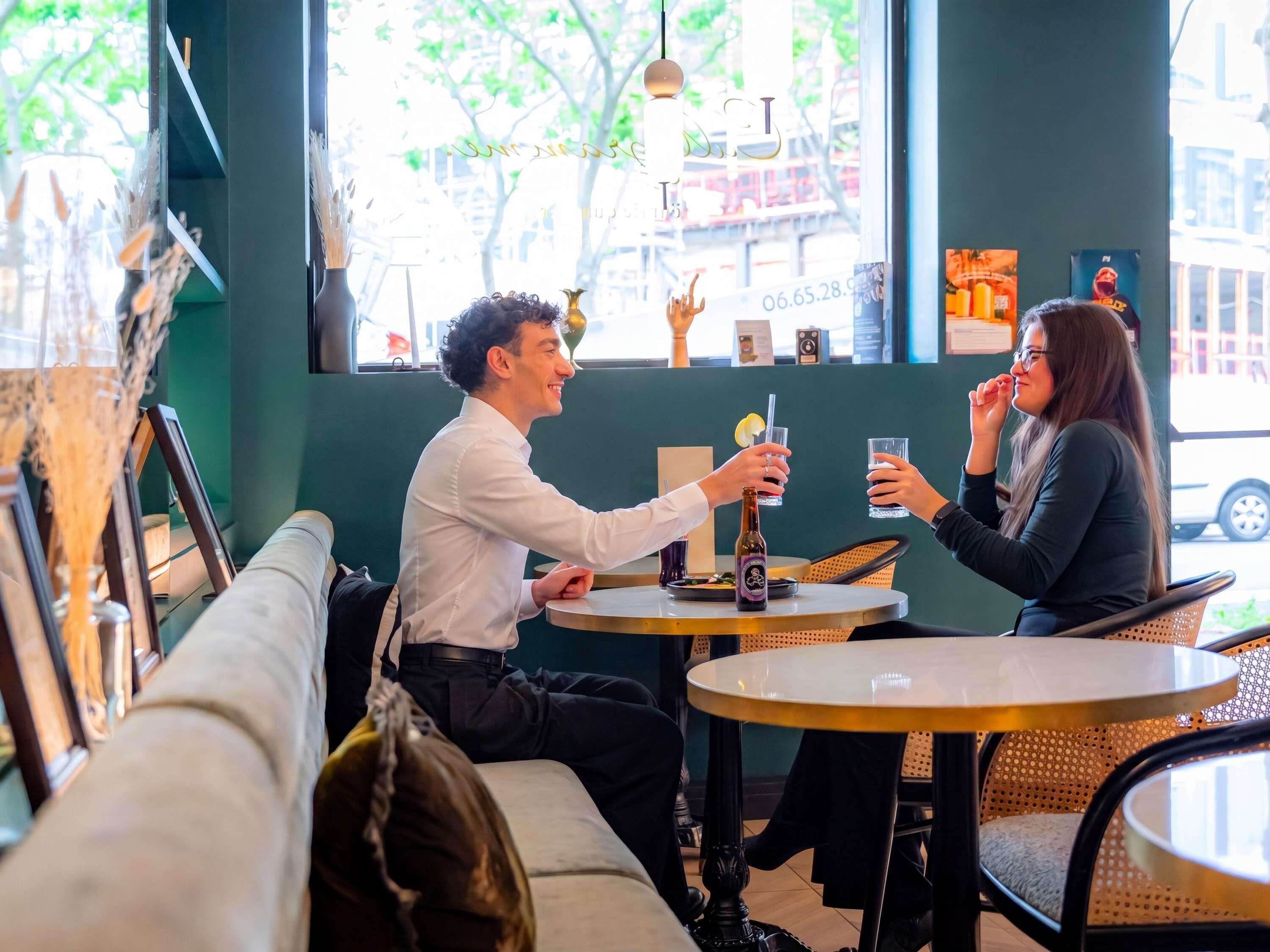 Een café met een groene inrichting, ronde tafels en een bank.