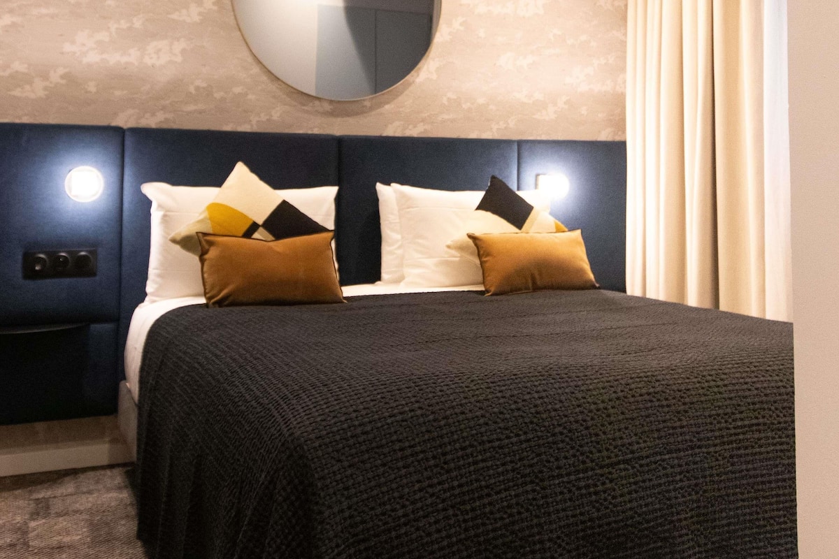 Una habitación de hotel con una cama, un espejo redondo y una mesita de noche.