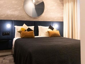 Ein Hotelzimmer mit einem großen Bett, einem runden Spiegel und einem Nachttisch mit einer Lampe.
