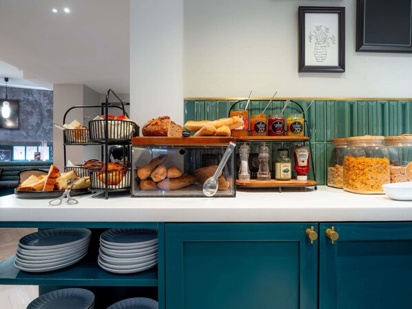 Un mostrador de buffet con diversos alimentos, incluyendo pan, salsas y frascos de conservas.