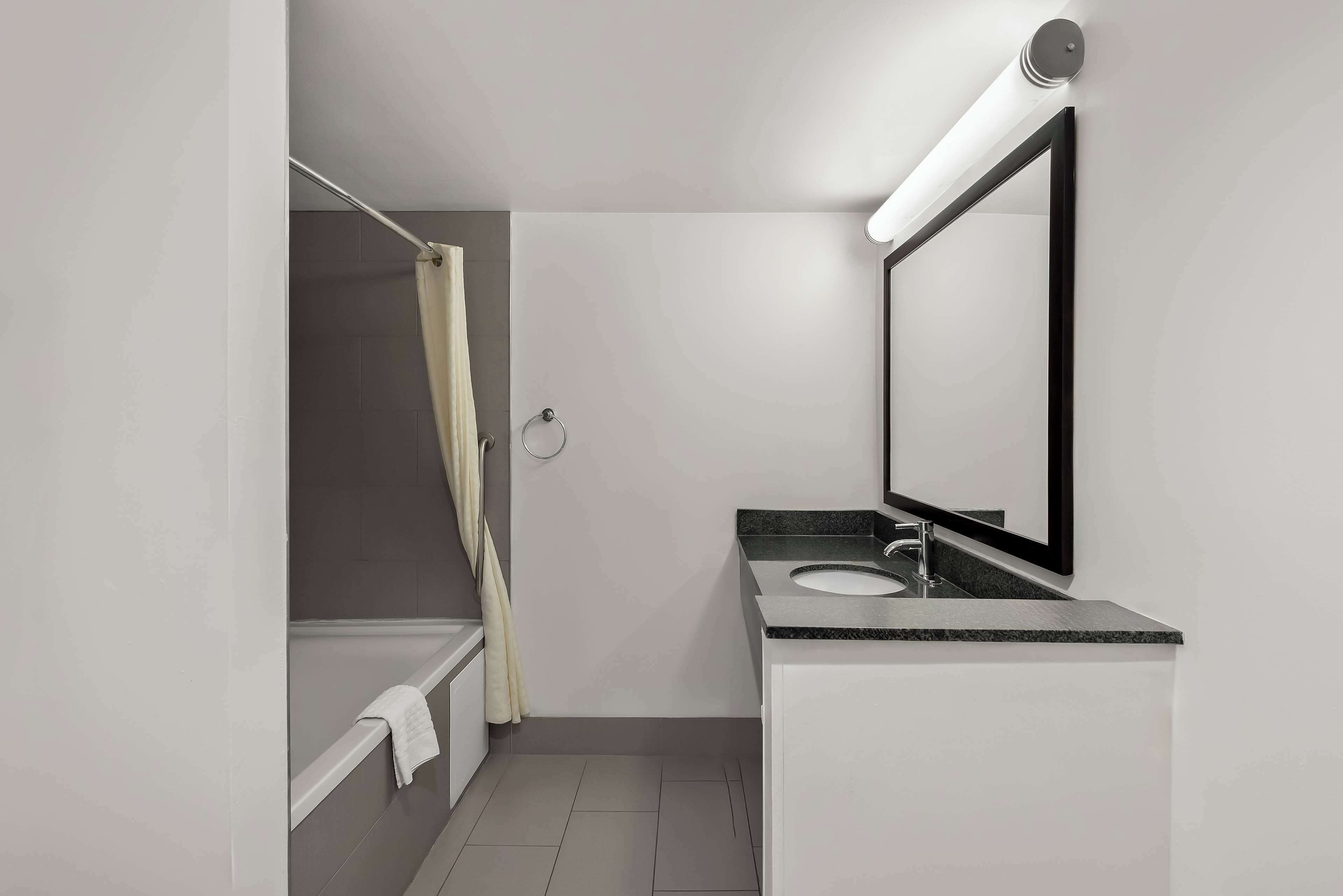 A modern bathroom with a bathtub, a sink, and a mirror.