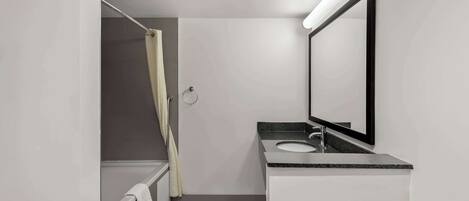 A modern bathroom with a bathtub, a sink, and a mirror.
