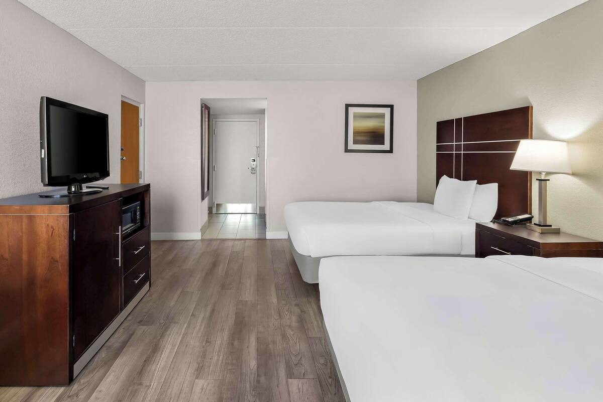 Une chambre d’hôtel avec deux lits, une télévision, un bureau et une lampe.