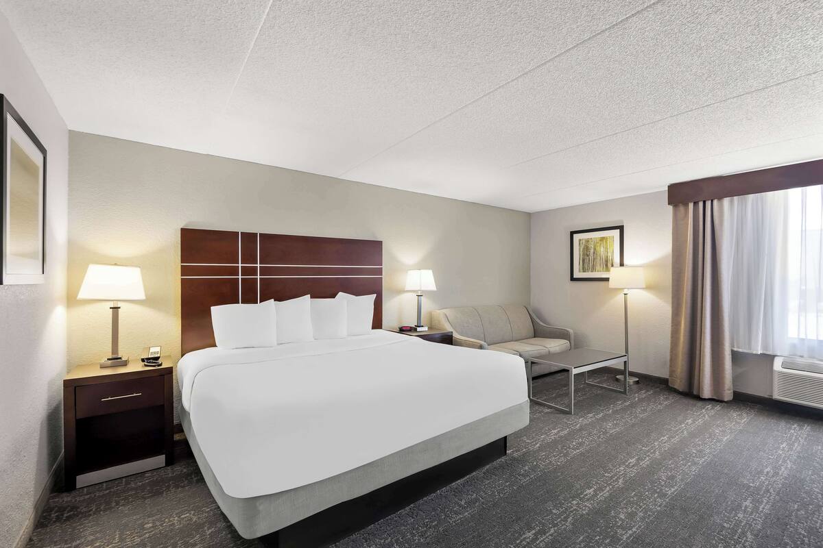 Une chambre d’hôtel avec un grand lit, deux tables de chevet avec des lampes, un canapé et une petite table.