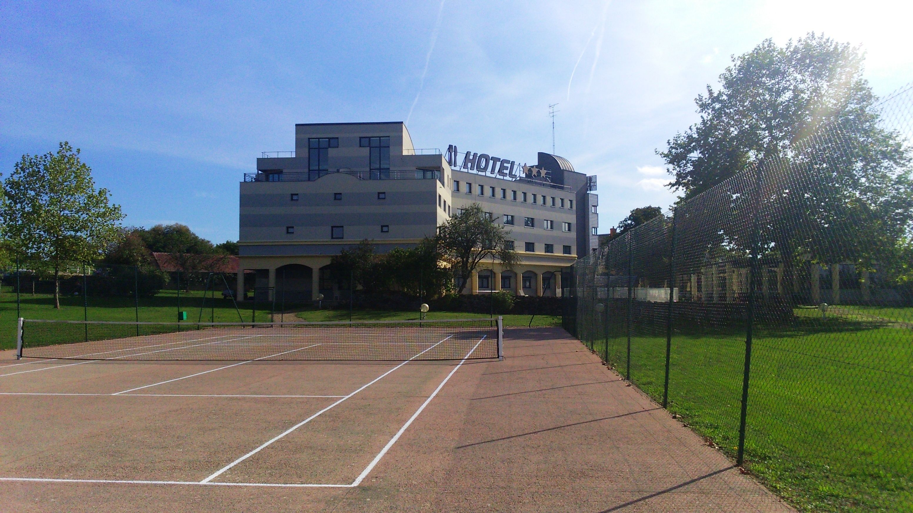 Un hotel con cancha de tenis al frente.
