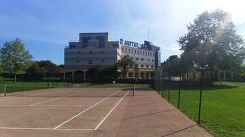 Un hotel con cancha de tenis al frente.