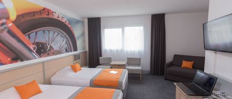 A hotel room with two beds, a desk with a laptop, a TV, and a large window with curtains.