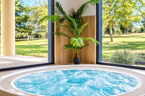 Un jacuzzi con vista a un jardín y árboles.