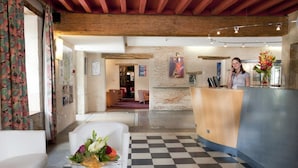 A reception area with a checkered floor, a reception desk, and a white sofa with a floral arrangement.