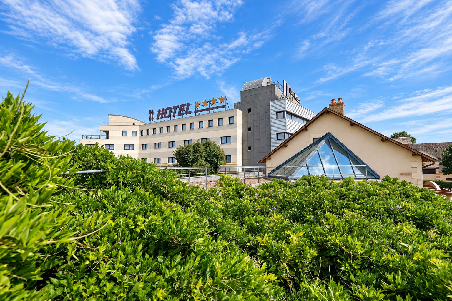 Een hotel met een moderne gevel, een opvallend bord en een helderblauwe lucht.