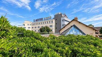 Et hotel med en moderne facade, et markant skilt og en klar blå himmel.