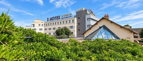 A hotel with a modern facade, a prominent sign, and a clear blue sky.