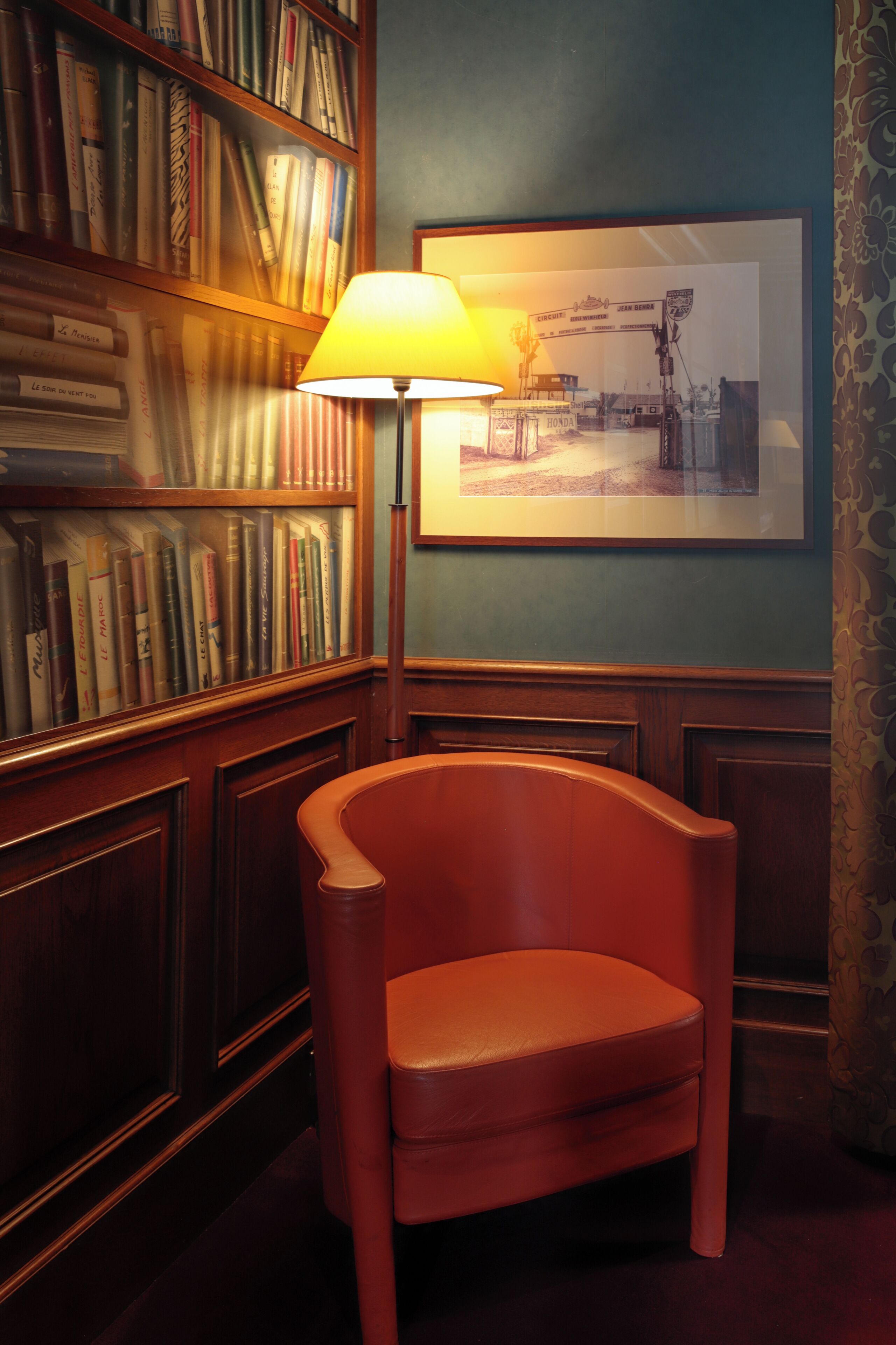 A room with a wooden bookshelf, a framed picture on the wall, and a single chair.