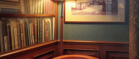 A room with a wooden bookshelf, a framed picture on the wall, and a single chair.