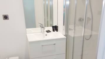 A bathroom with a white toilet, a sink with a mirror above it, and a glass shower enclosure.