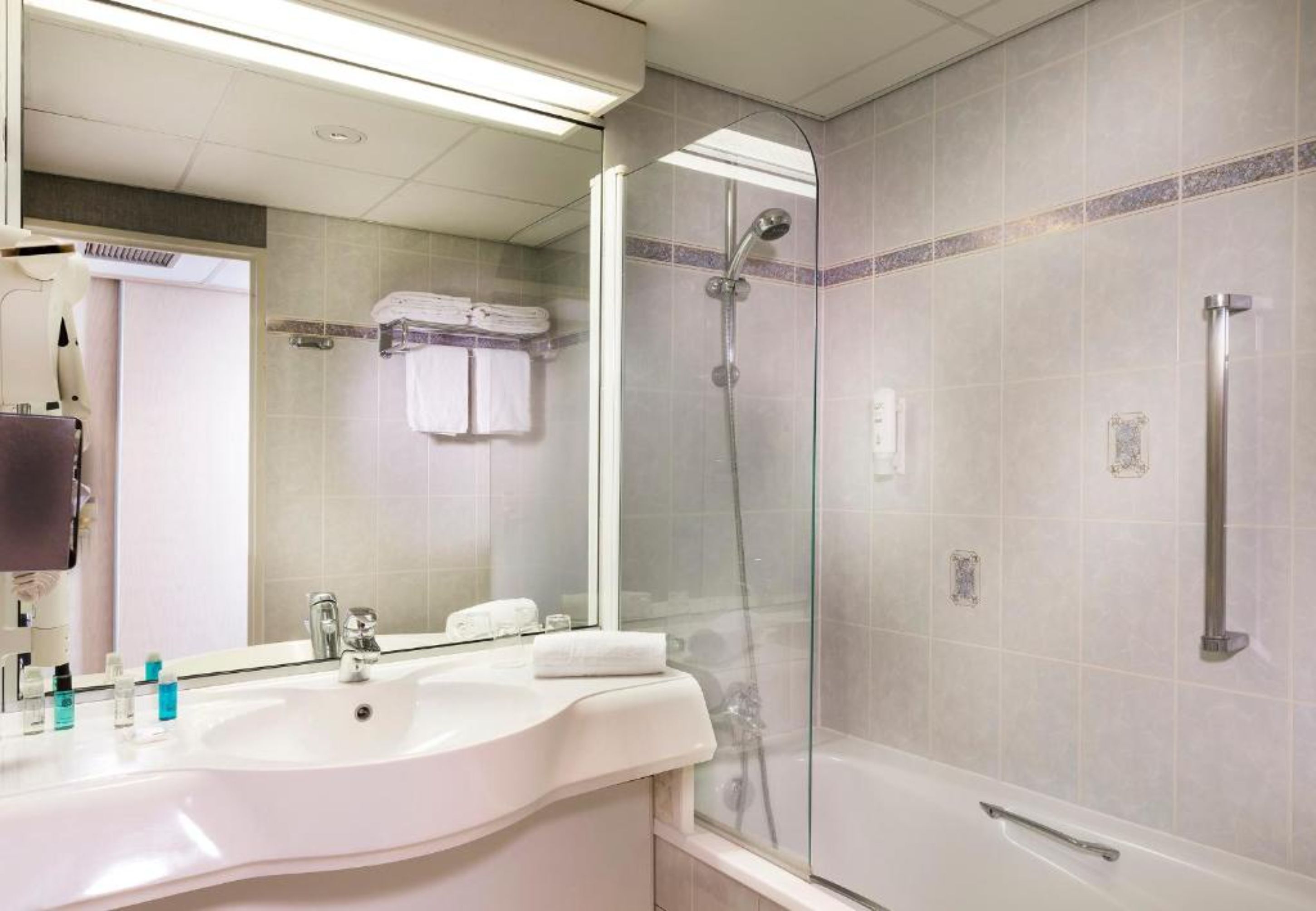 Un bany modern amb dutxa envidriada, un lavabo amb articles de tocador i un mirall.