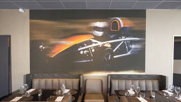 A restaurant with booth seating and a large screen displaying a racing car.