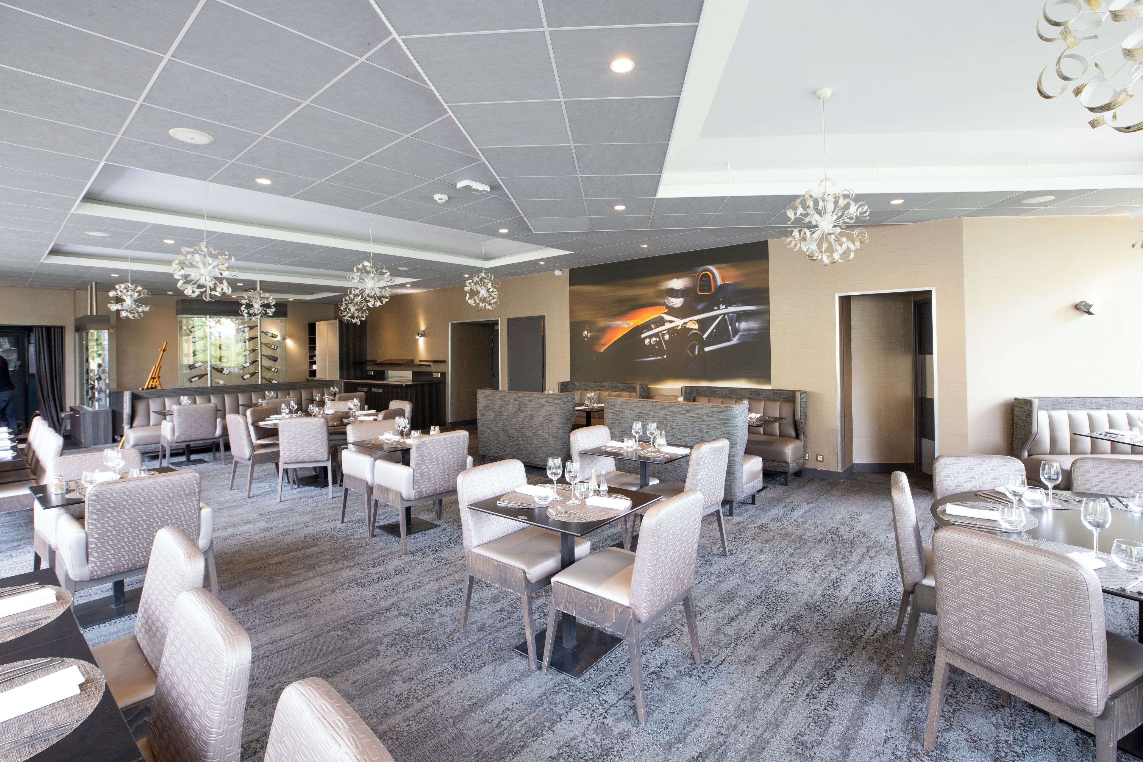 A modern hotel lobby with multiple dining areas, comfortable seating, and a large wall mural.