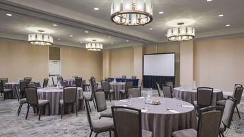 A conference room with round tables, chairs, and a projector screen.