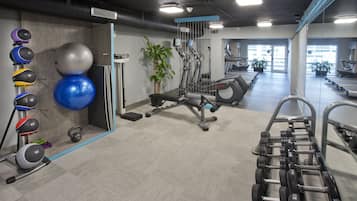 A gym with exercise equipment, treadmills, and a mirror wall.