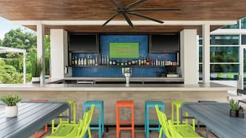 A bar area with a ceiling fan, a sign reading 'The Spaniard,' and a variety of bottles and cans. There are colorful stools and a table with chairs.