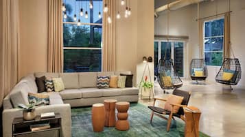 A modern living room with a sofa, coffee table, hanging chairs, and a large window with curtains.