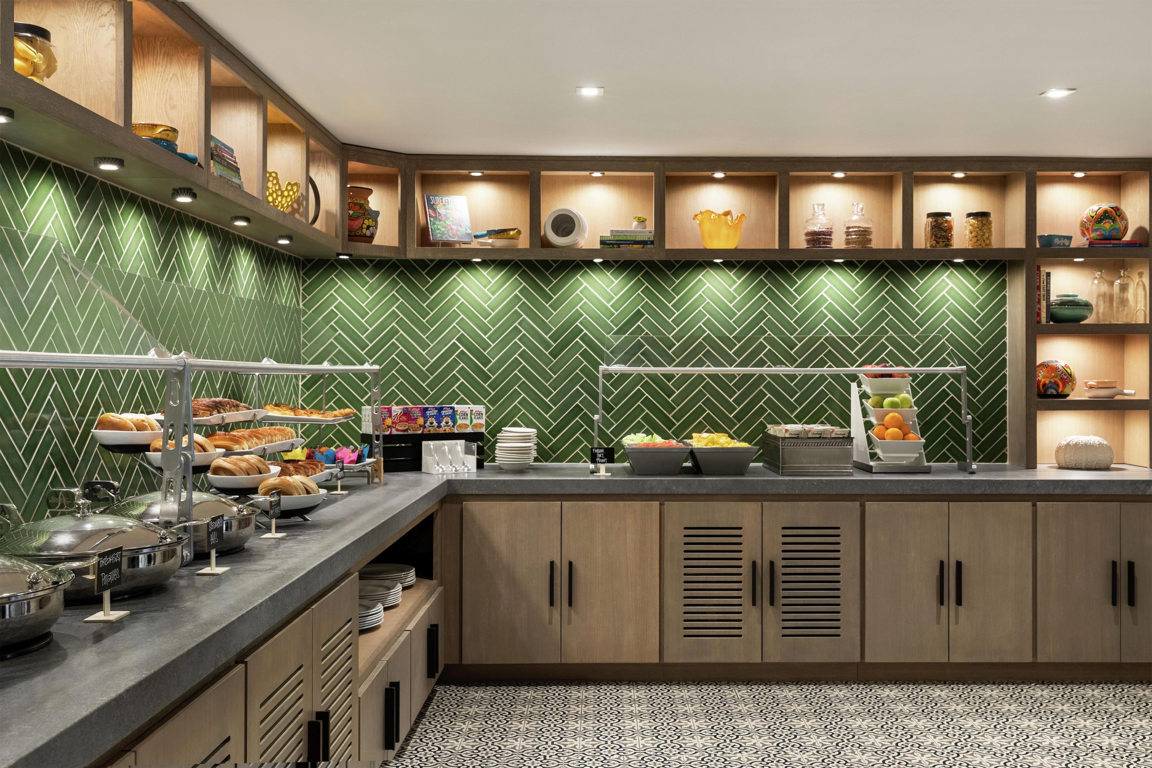 Un espace buffet proposant divers plats et un mur décoré d’un motif à chevrons verts.