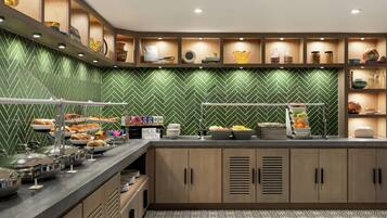 Un espace buffet proposant divers plats et un mur décoré d’un motif à chevrons verts.