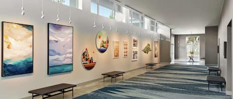 A modern art gallery with a long corridor, benches, and a patterned carpet.
