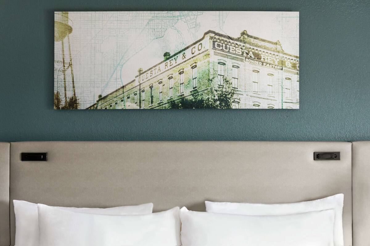 Ett hotellrum med en stor väggkarta som visar en byggnad, och på kartan står det "CUESTA REY & CO. BONDED FACTORY".