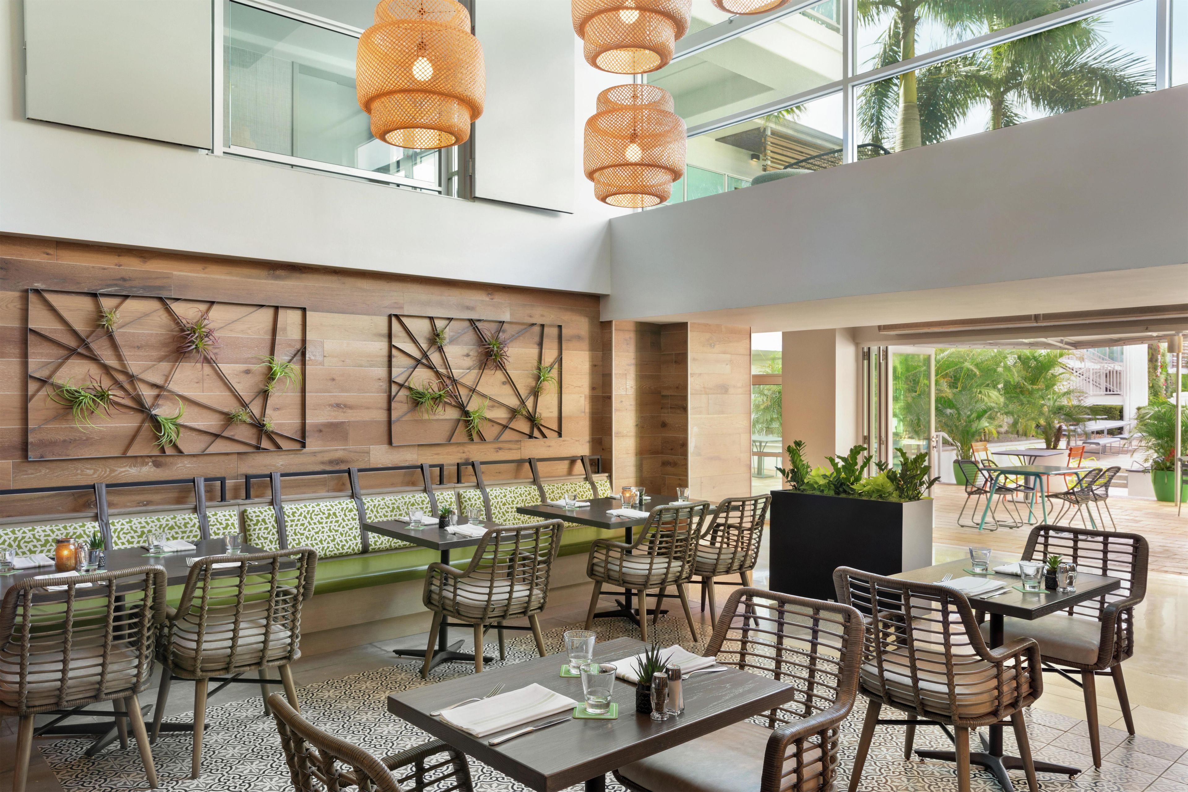 An indoor dining area with wicker furniture, wooden walls, and a view of the outdoors.