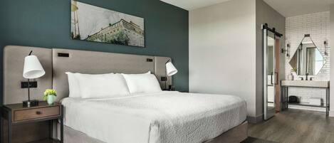 Un dormitorio moderno con una cama grande, lámparas de noche, una mesita de noche y un cuadro colgado en la pared.