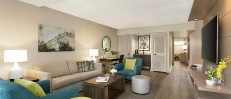 A modern living room with a sofa, armchairs, a coffee table, and a TV.
