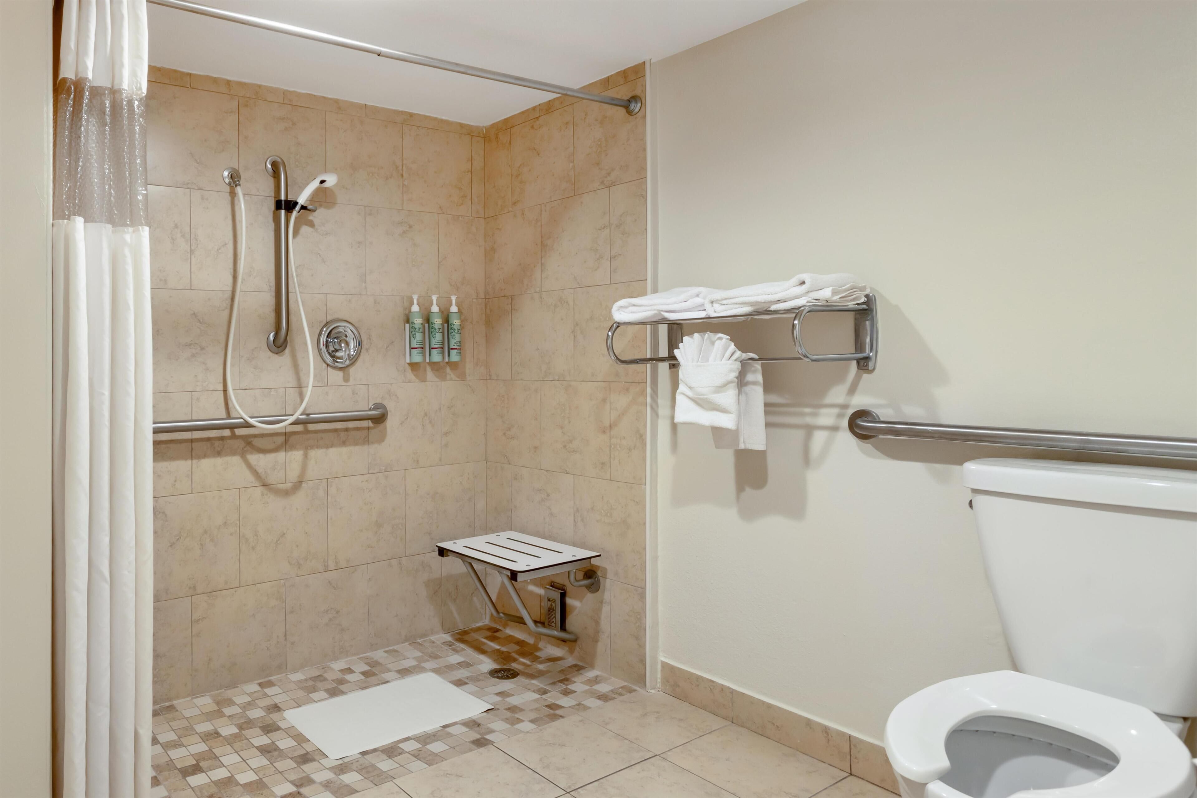 A bathroom with a shower, toilet, and a towel rack.