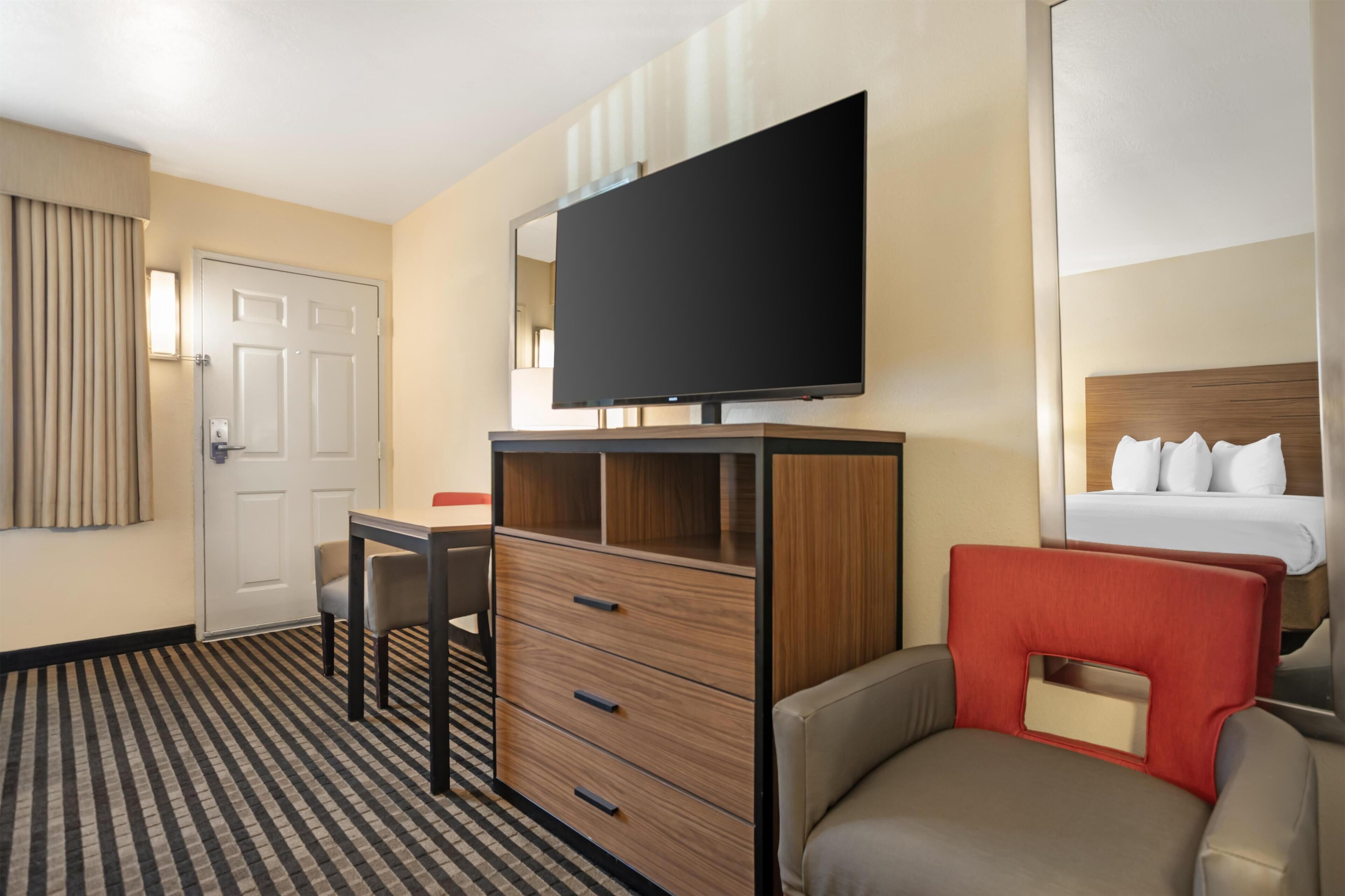 Una camera d'albergo con un letto, una televisione, una scrivania e una sedia.