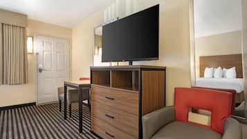 Une chambre d’hôtel avec un lit, une télévision, un bureau et une chaise.