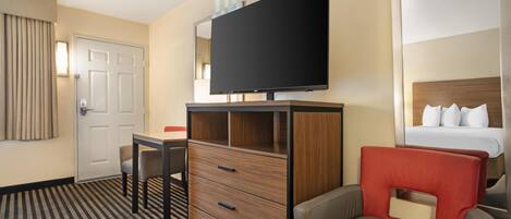 A hotel room with a bed, a TV, a desk, and a chair.