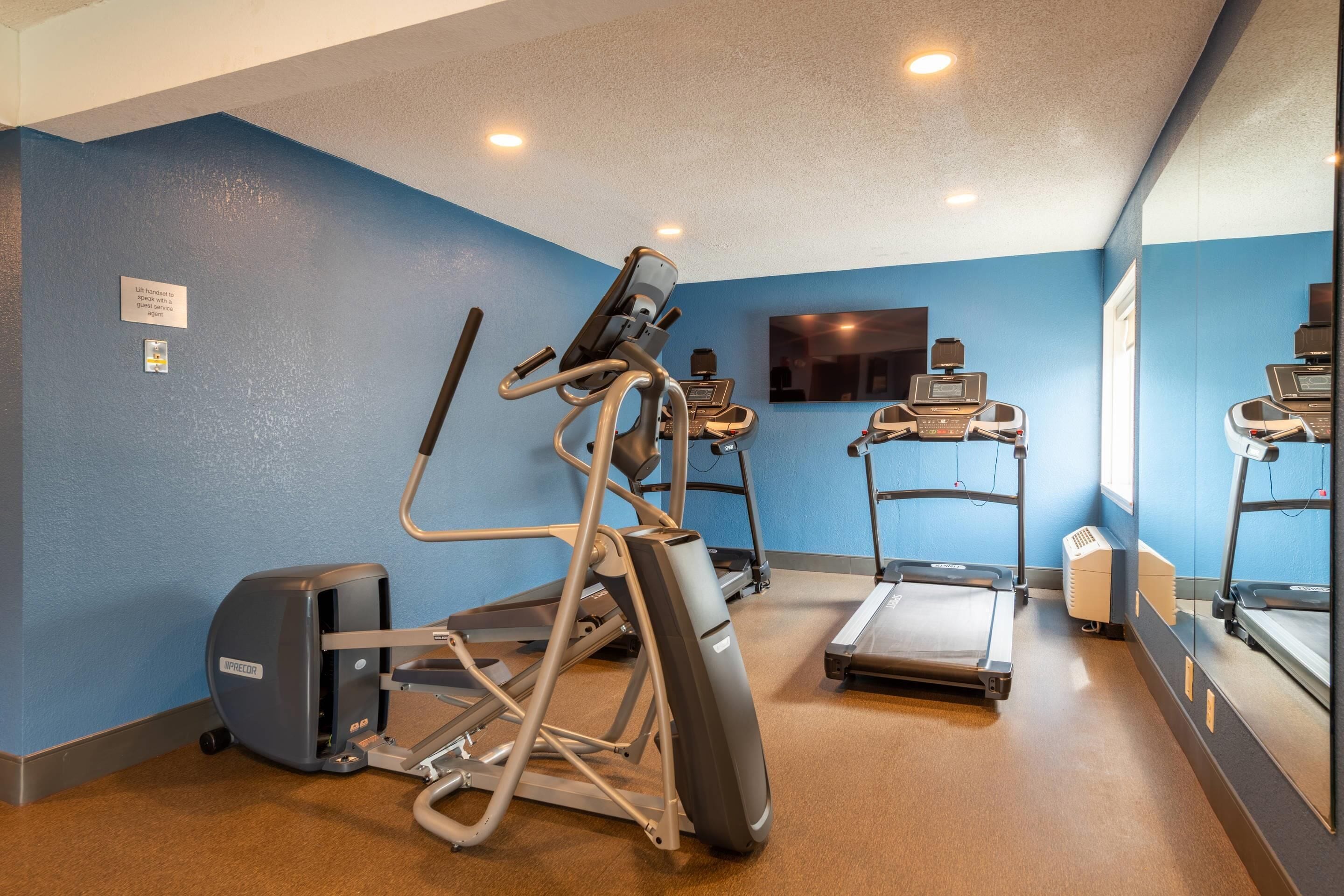 A fitness room with exercise equipment including a stair climber, elliptical, and treadmills.