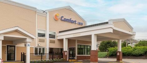 A Comfort Inn hotel with a covered entrance, a parking lot, and a clear sky.