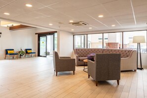 Un hall d’entrée spacieux, doté d’un grand espace salon, d’un comptoir d’accueil et offrant une vue sur l’extérieur grâce à de grandes fenêtres.
