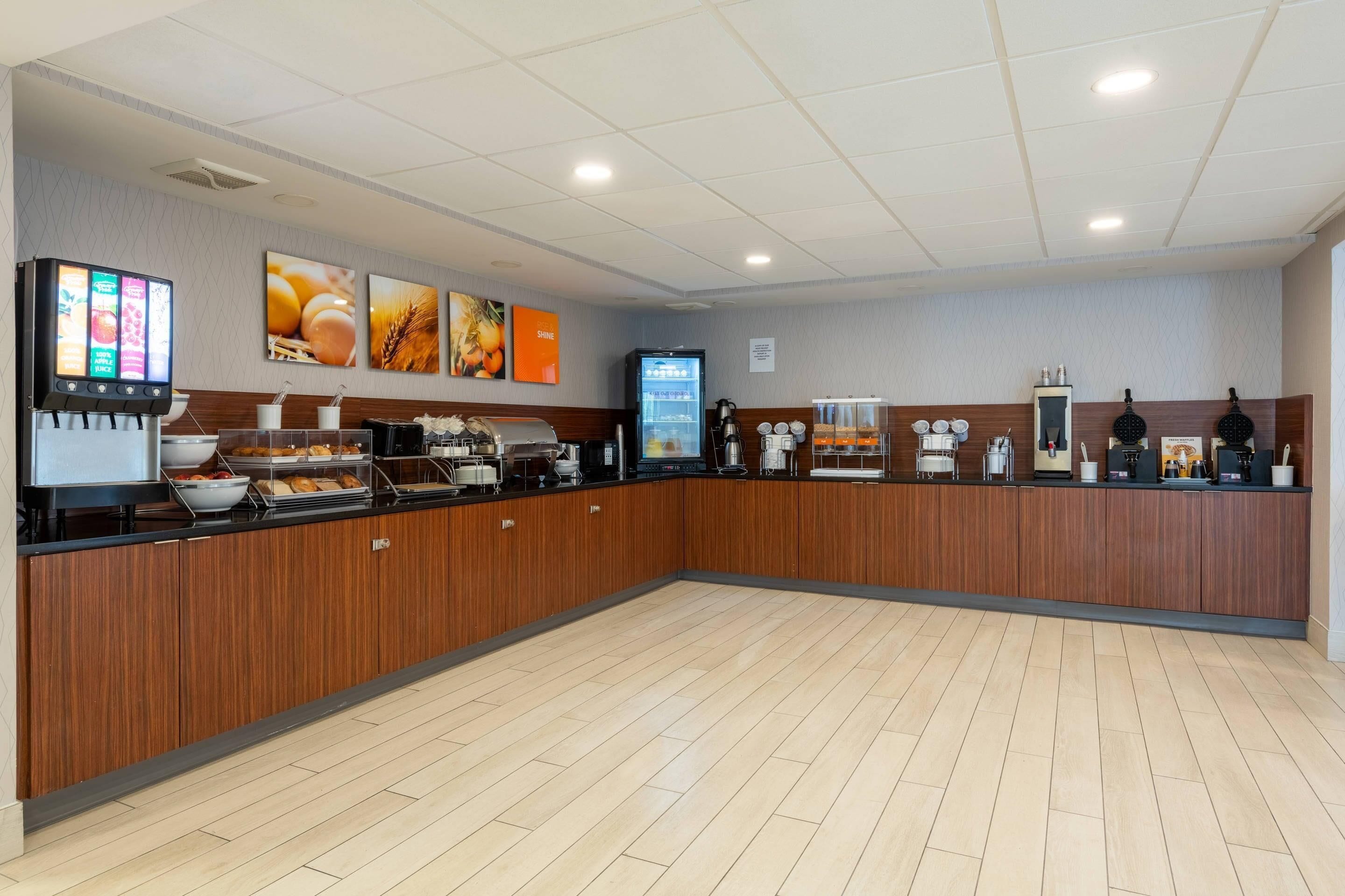 A breakfast area with a self-serve station, coffee machines, and a digital menu display.