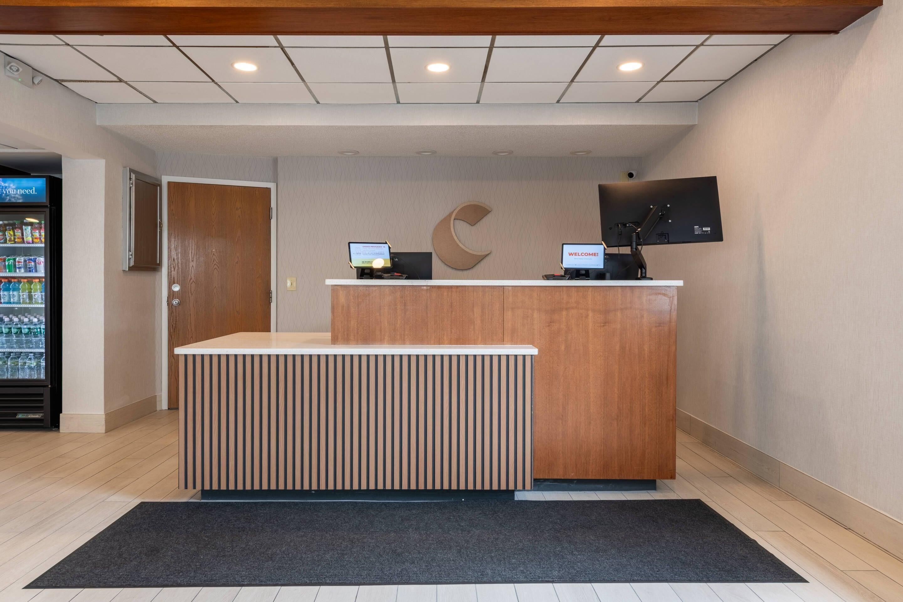 A reception desk with a computer monitor, a large C-shaped logo on the wall, and a vending machine to the left.